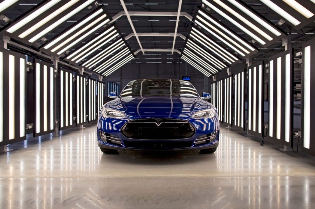 A SLEAK, MIDNIGHT BLUE CAR SITS IN A TUNNEL OF LIGHT BARS